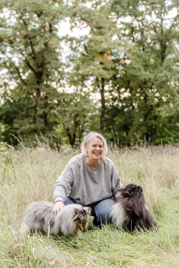 Hundefriseurin Antje Schwirz mit zwei Hunden in einer Wiese